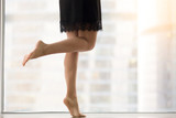 Female bare legs, staying on tiptoe, healthy legs, smooth skin, helping mind and body relax and rejuvenate after work, taking dancing classes, exercising at morning at window with city view. Close up