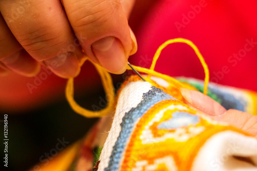 The cross stitching. Photo of woman hands closeup, which holds the needle and the embroidering. Selective focus. 5