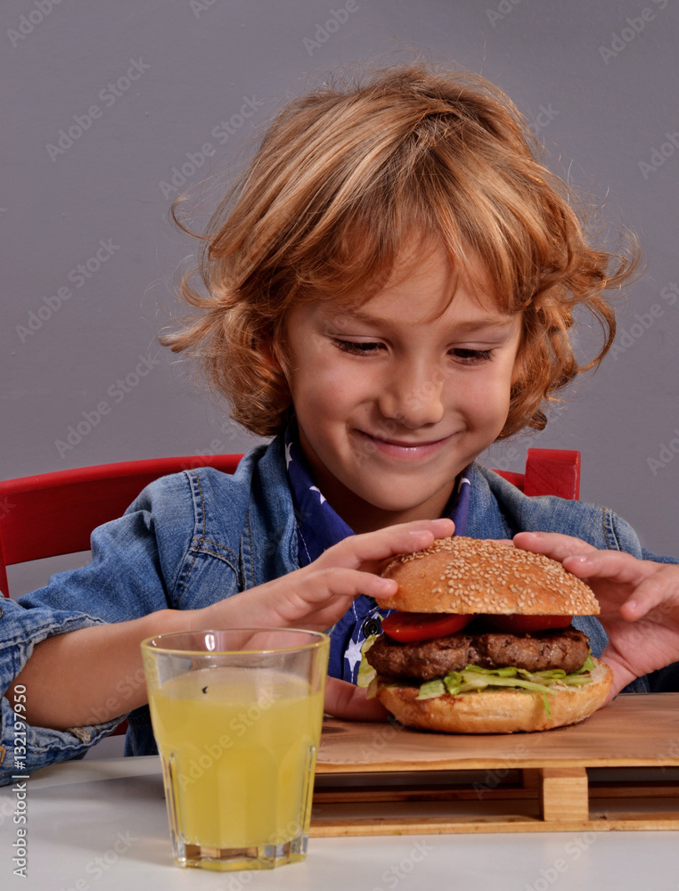 niño contento comiendo hamburguesa y refresco.
