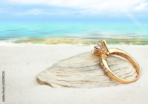 Jewellry ring with big diamond on sand beach with copy space, so
