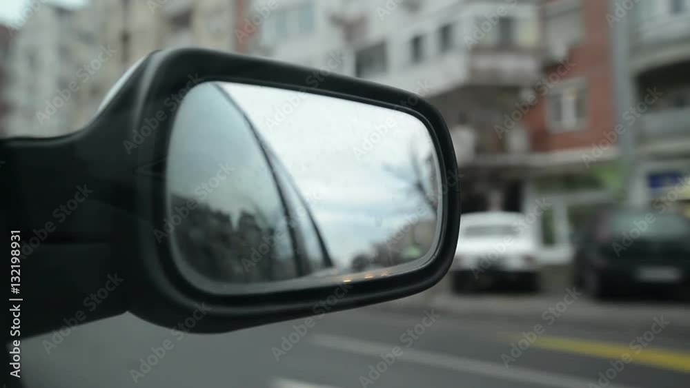 Driving through urban district, reflection in the car side mirror Driving through urban district, reflection in the car side mirror