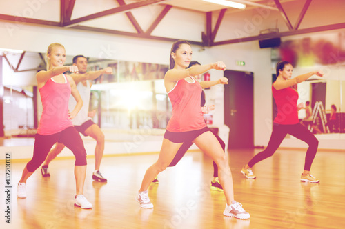 group of smiling people exercising in the gym