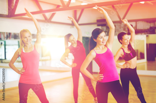 group of smiling people stretching in the gym