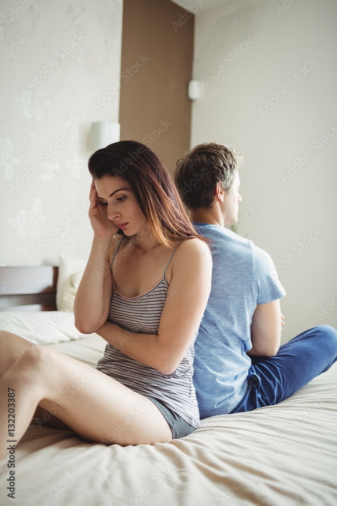 Couple ignoring each other sitting back to back on bed Couple ignoring each other sitting back to back on bed