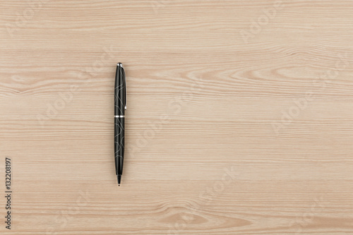 Black ballpoint pen lies on a wooden texture