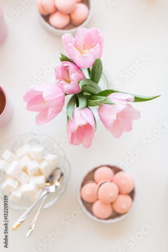 Spring background. Sweets and tea on a table with pink tulips.