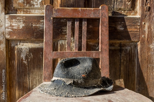 Battered old hat damaged by clothes moth on vintage background. A forgotten hat covered with spider web among the ruins of a house. Imagine the owner of this hat and tell their story.