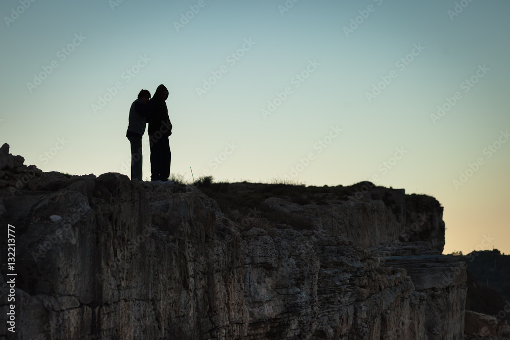 Silhouette of a couple on the ridge of a hill at dusk time