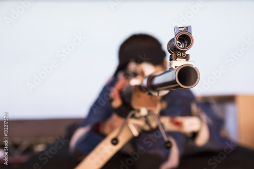 Woman with a sporting rifle aiming in a shooting range photo