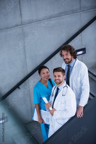 Doctors and nurse holding medical reports standing on stairs photo