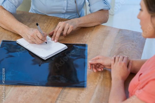 Doctor writing a prescription for her patient in medical office