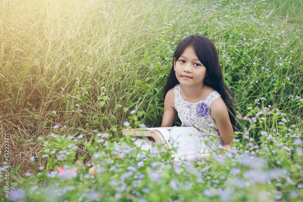 Cute asian girl Reading book at meadow in holiday Cute asian girl Reading book at meadow in holiday