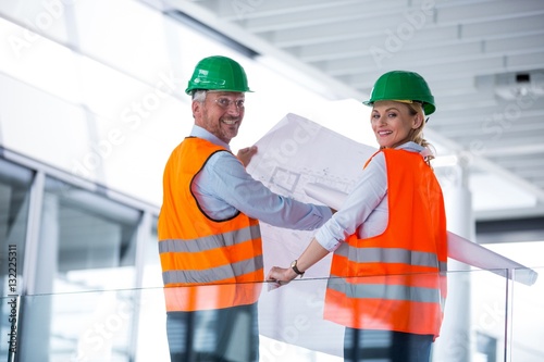 Architects discussing with blueprint in office corridor