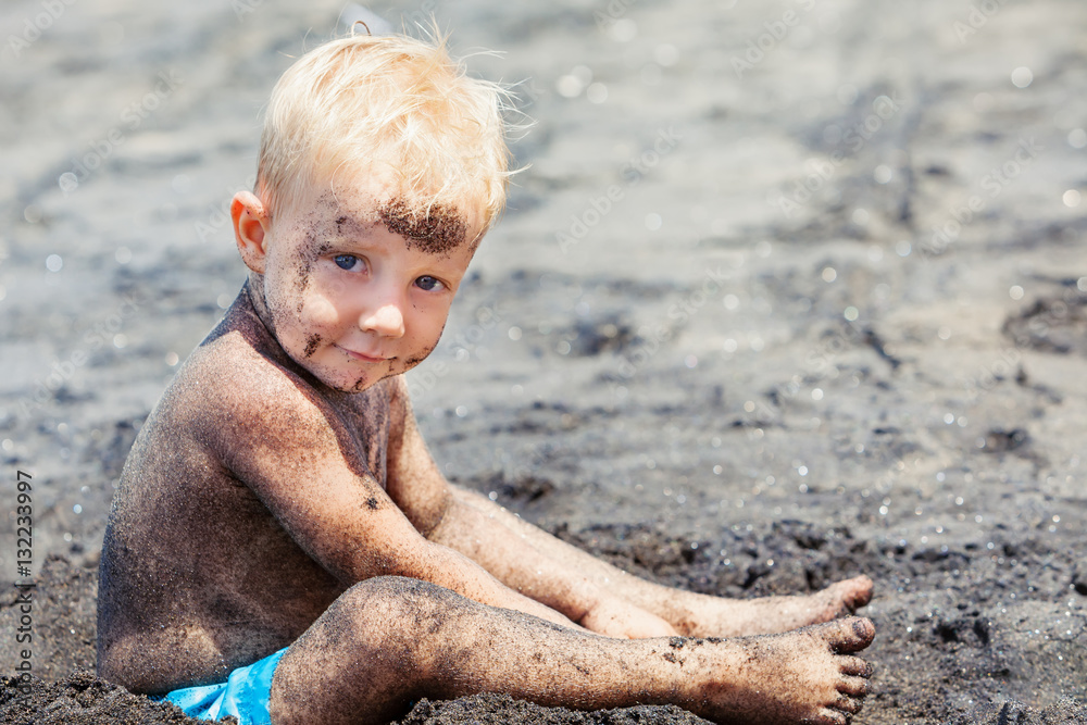 Funny photo of happy baby boy with dirty body and sly face playing game  with fun