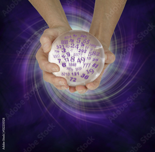 What are your lucky numbers - female hands cupped around a large crystal ball with random numbers emerging  on a  purple black spiraling energy field background with copy space below photo