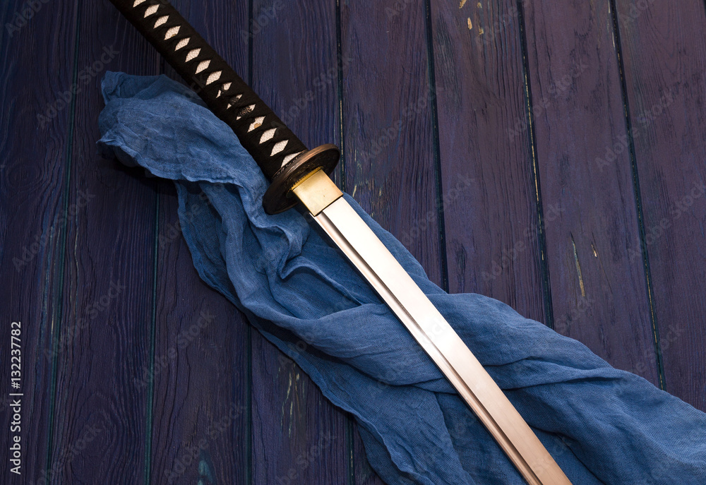 Naklejka premium miecz katana japonia na tle drewna z niebieskim szalem