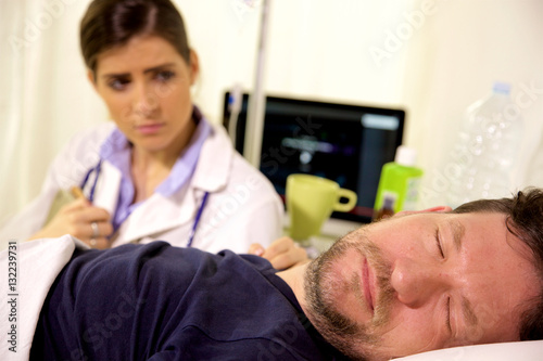 Doctor watching ill man in hospital sleeping