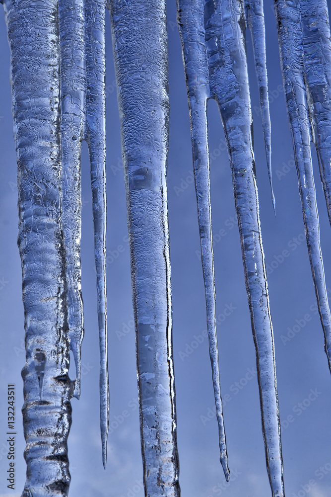 Close up of icicles against blue sky.