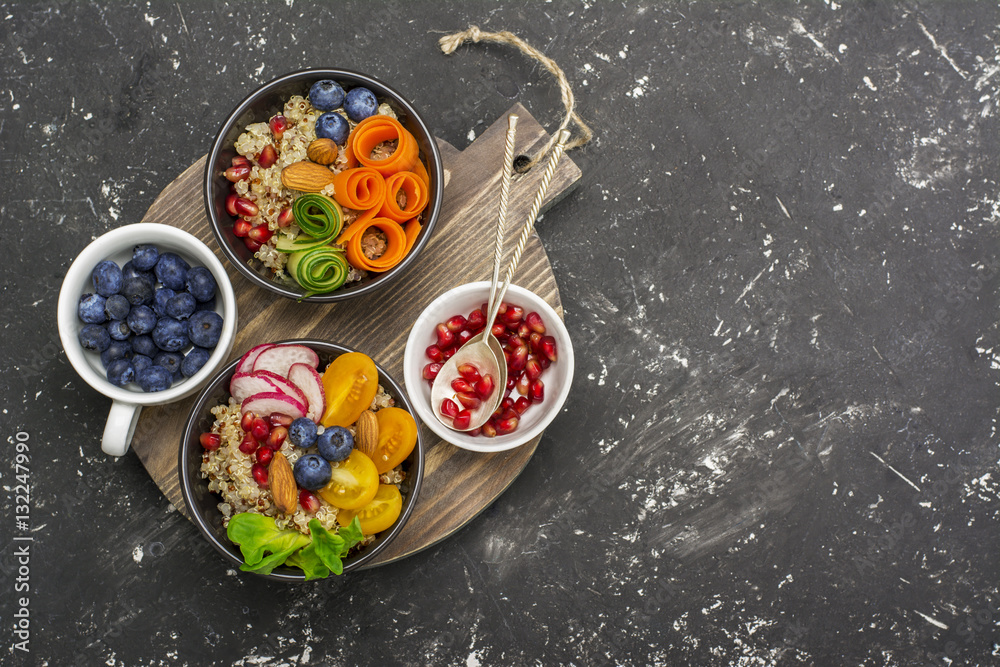 Vegetarian Quinoa bowl. Healthy breakfast or snack with detox , tomato, cucumber, carrot, pomegranate seeds, juicy blueberries and lettuce in portioned bowls. Top view Vegetarian Quinoa bowl. Healthy breakfast or snack with detox , tomato, cucumber, carrot, pomegranate seeds, juicy blueberries and lettuce in portioned bowls. Top view