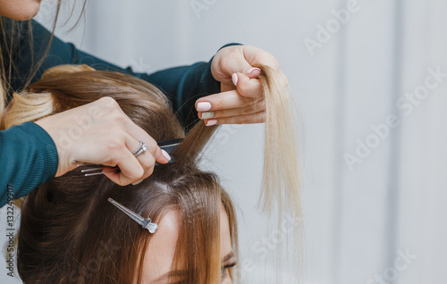 hands of woman combing hair and doing bouffant her client in beauty salon photo