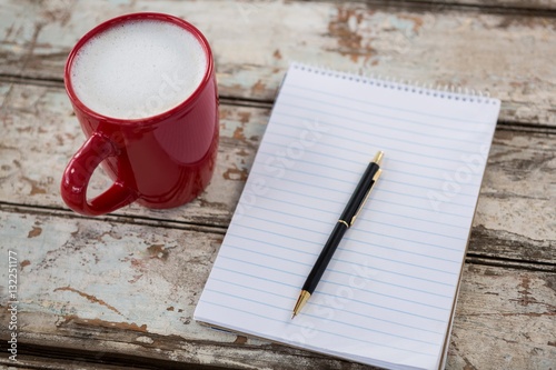Cup of coffee with blank notepad and pen