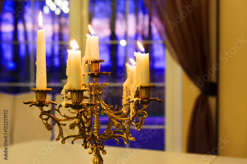 vintage candlestick with burning candles on a background of a window