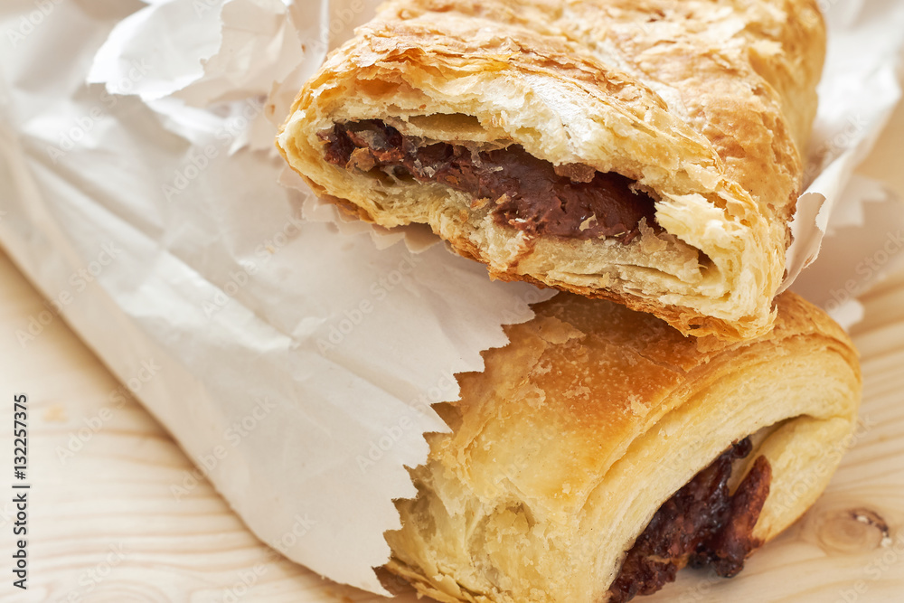Puff pastry with chocolate filling in white paper bag on wooden background Puff pastry with chocolate filling in white paper bag on wooden background