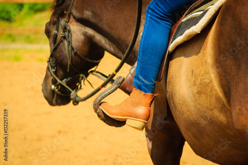 Woman foot in stirrup on horse saddle