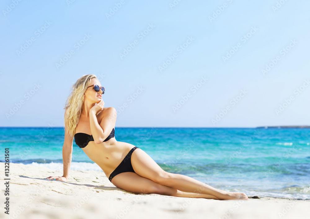 Young woman in a sexy bikini posing on the beach