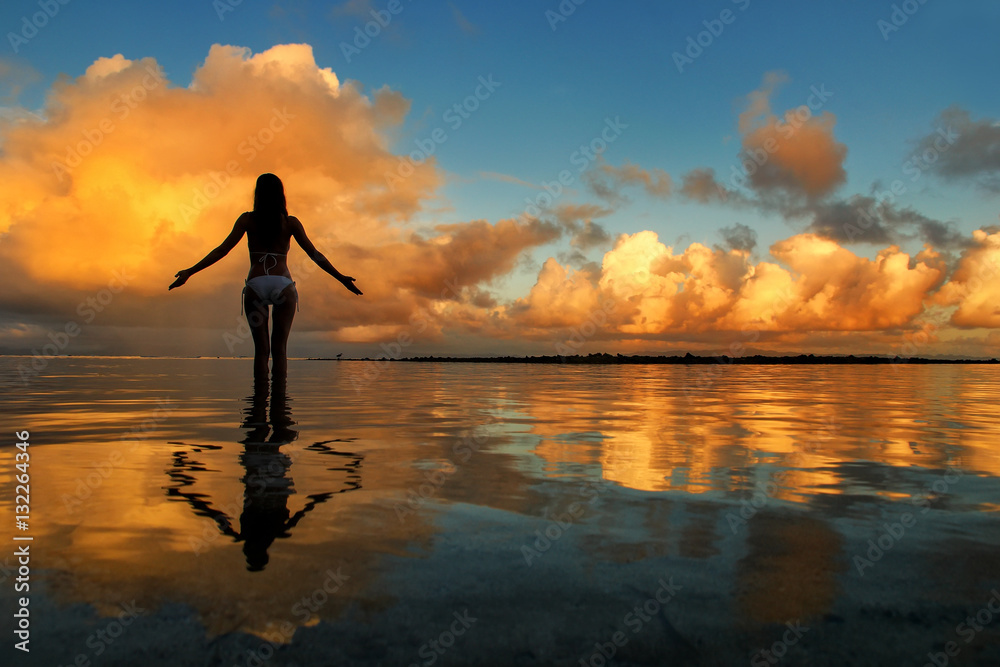 Silhouetted woman standing in a water at sunset on Taveuni Island, Fiji. Taveuni is the third largest island in Fiji.