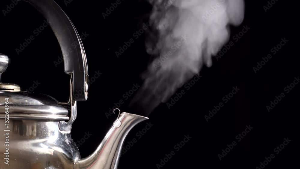 Boiling water in teapot on black background