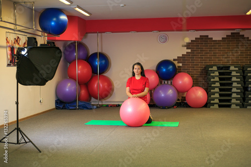 Young beautiful woman doing exercises with a fit ball at the fitness center