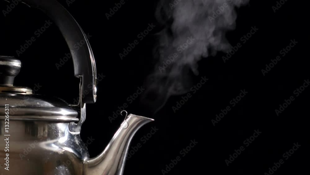 Boiling water in teapot on black background, slow motion