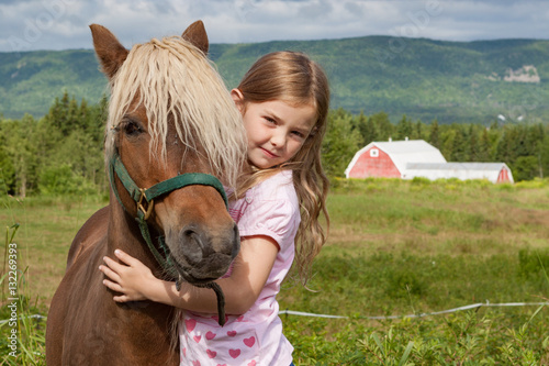 Little girl hugs her pony in Canadian countryside
