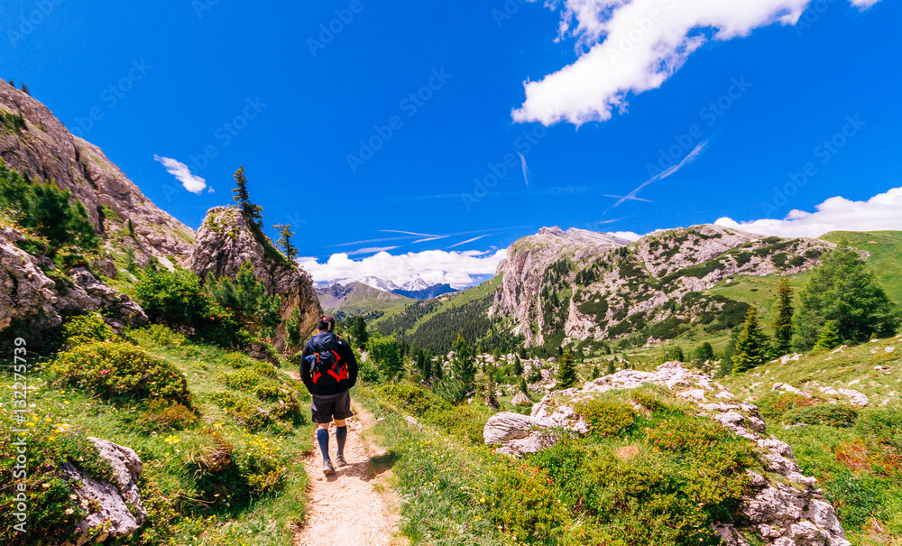 Dolomites, Italy, single hiker with backpack a and shorts walking on trail.