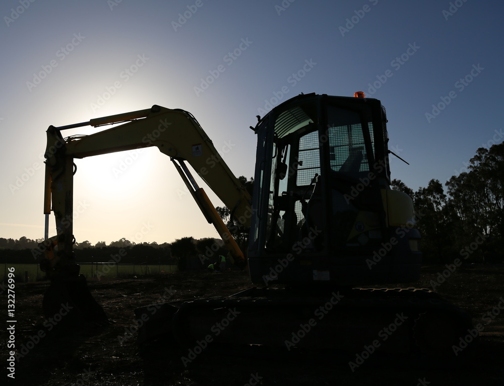 End of the workday. Excavator silhouetted against the sunset. End of the workday. Excavator silhouetted against the sunset.