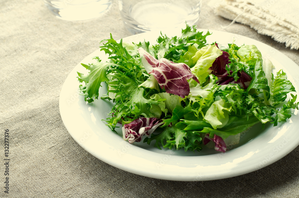 Green salad with spinach, frisee, arugula and radicchio on blue wooden background Green salad with spinach, frisee, arugula and radicchio on blue wooden background