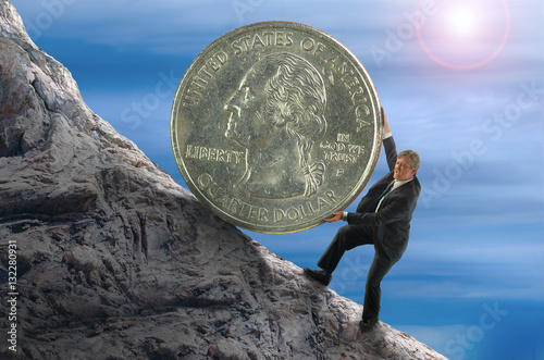 Sisyphus metaphor showing man struggling to roll a giant coin up hill representing financial stress, business struggles, stock market success, economic hardship, personal struggles and determination. photo