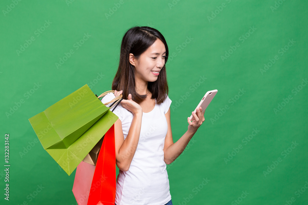 Woman holding shopping bag and looking at mobile phone Woman holding shopping bag and looking at mobile phone