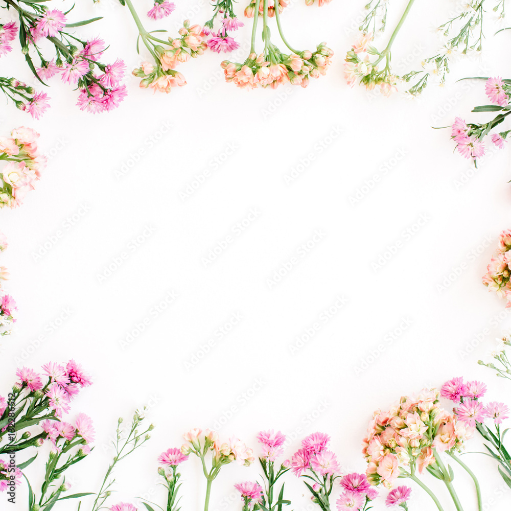 Round frame of colorful wildflowers, green leaves, branches on white background. Flat lay, top view. Valentine's background