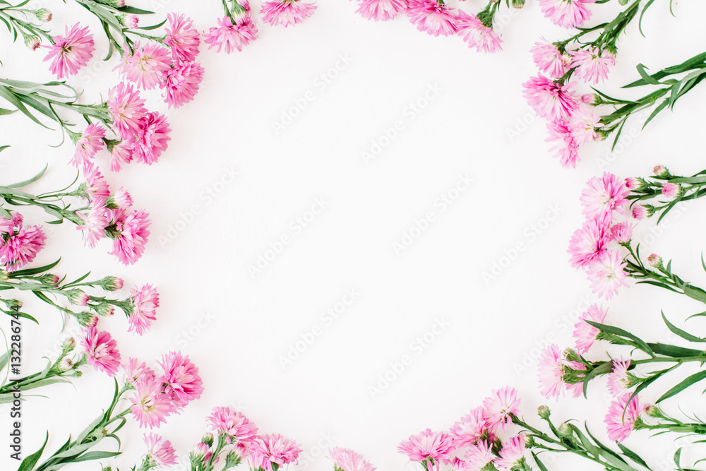 Wreath frame made of pink wildflowers, green leaves, branches on white background. Flat lay, top view. Valentine's background