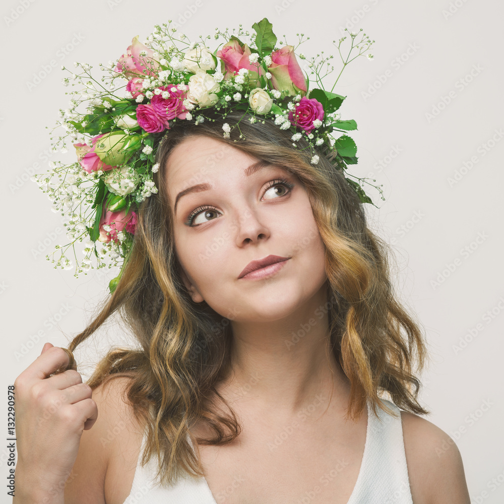 Portrait of a playful young girl in a wreath of roses