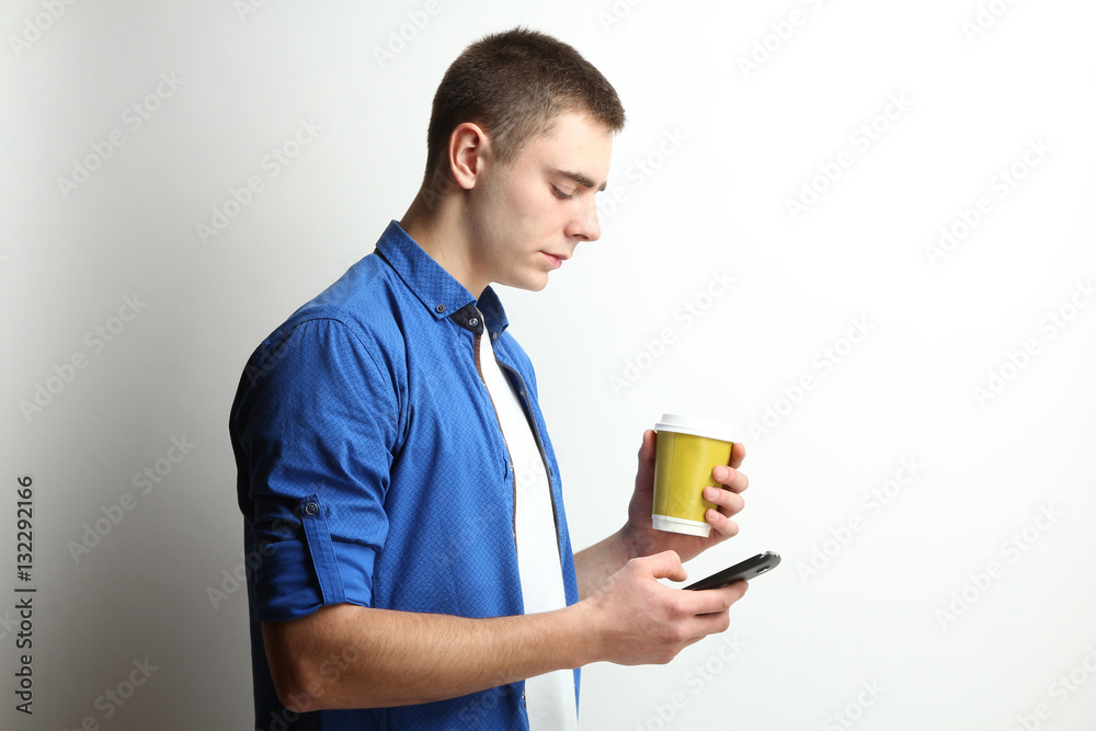 boy in a blue shirt with a phone on a white background