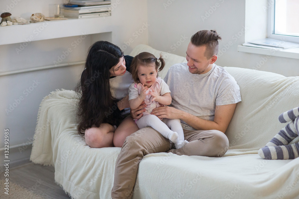 Happy young family of three sitting on the couch Happy young family of three sitting on the couch