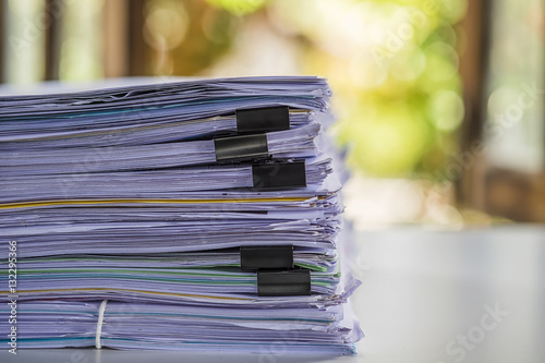 Stack of business report paper file on modern white office desk with bokeh background. photo