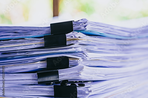 Stack of business report paper file on modern white office desk with bokeh background. photo