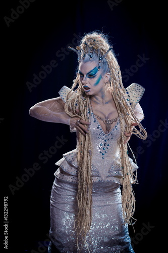 emotional actress woman in makeup and costume queen of elves or snow queen on blue-black background photo