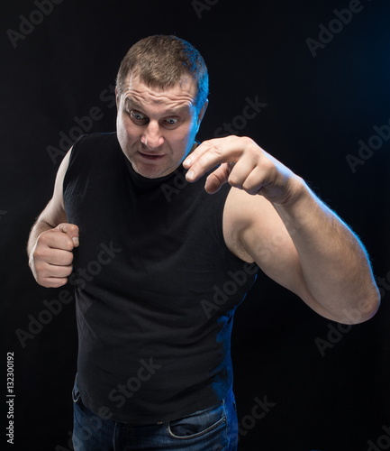 Brutal man actor gesticulates and grimaces on a black background. photo