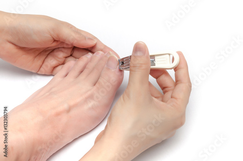 Obraz na płótnie Using nail cutter to cut toenails on white background isolated w salonie