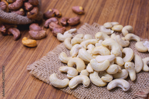 roasted cashew nuts with shell in gunny bag and on wooden background.